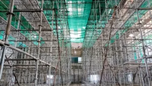 Interior view of reusable modular steel scaffolding and green safety netting, demonstrating sustainable construction practices through the use of recyclable materials and efficient site resource management.