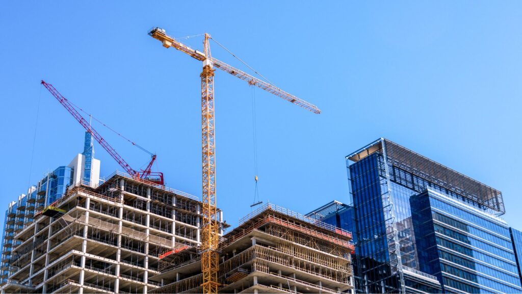 A high-rise building under development by construction companies in London featuring a large yellow tower crane against a clear blue sky.