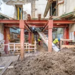 A deep basement excavation site in London featuring steel propping and conveyors, managed by specialist basement construction contractors in London.