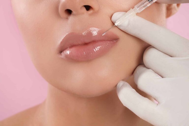 Young woman getting lips injection on pink background, closeup