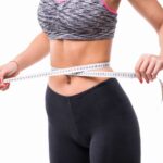 young blonde fitness Woman measuring her body with ruler dressed in fasion sportswear losing weight concept