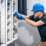 male-electrician-works-switchboard-with-electrical-c