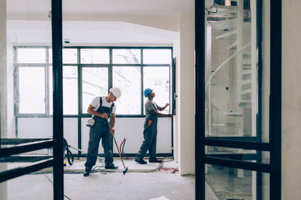 Two professional cleaners in safety gear and hard hats performing post-construction cleanup in a newly renovated London building, showcasing expert construction site cleaning services in UK.