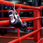 Boxing gloves in a boxing ring with bags in the gym.