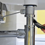 Close-up of plumber's hand doing repairing work at the sink.