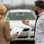 Young man and woman in a car rental service standing while looking at car.