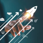 A professional touching a screen showing rising growth arrows, business icons, and a launching rocket symbolising a successful B2B marketing campaign.